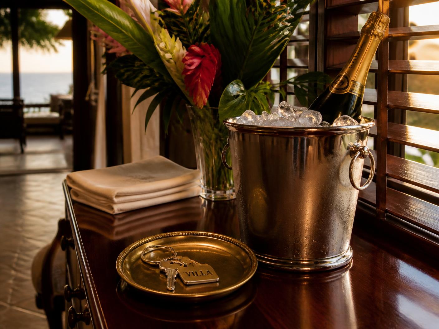 Chilled champagne, tropical flowers, and villa keys on a polished console